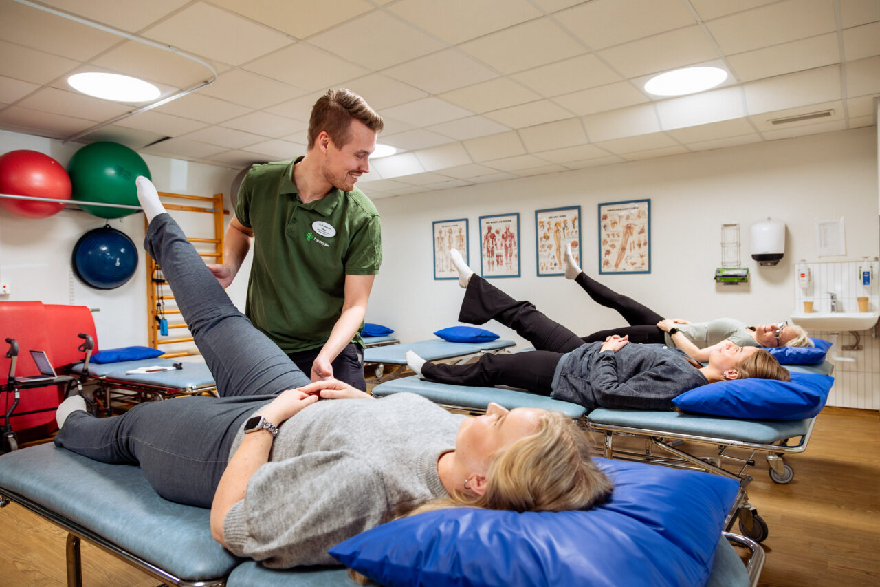 En fysioterapeut tränar tre patienter i liggande ben-övningar