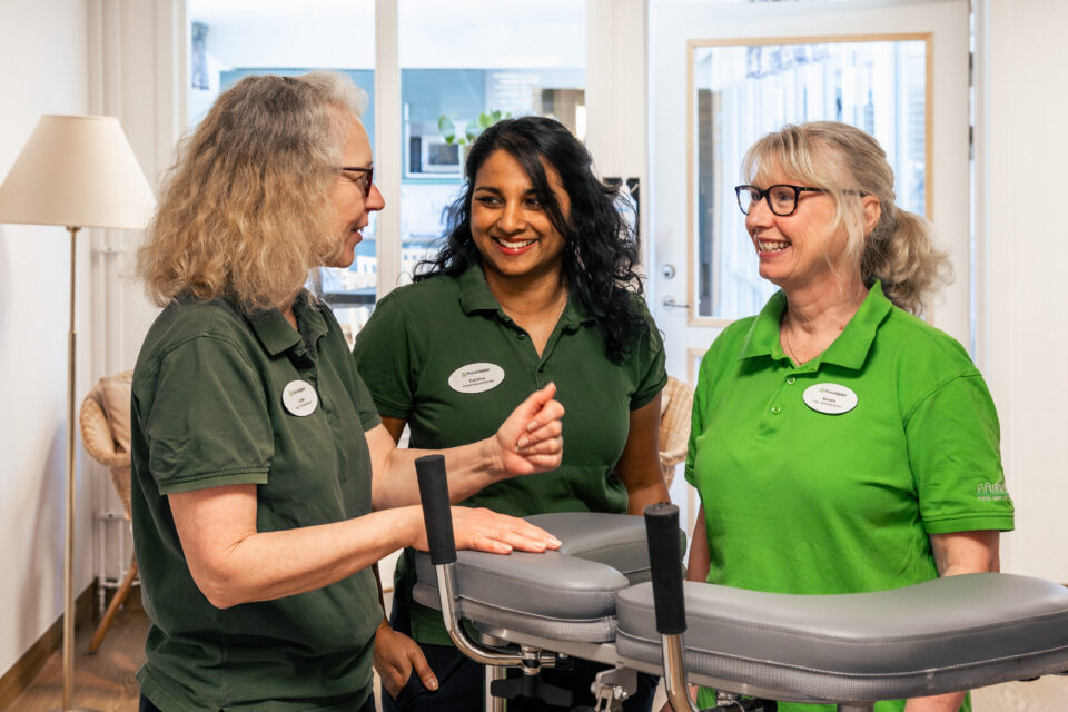 tre kvinnor i arbetskläder som står och ler mot varandra